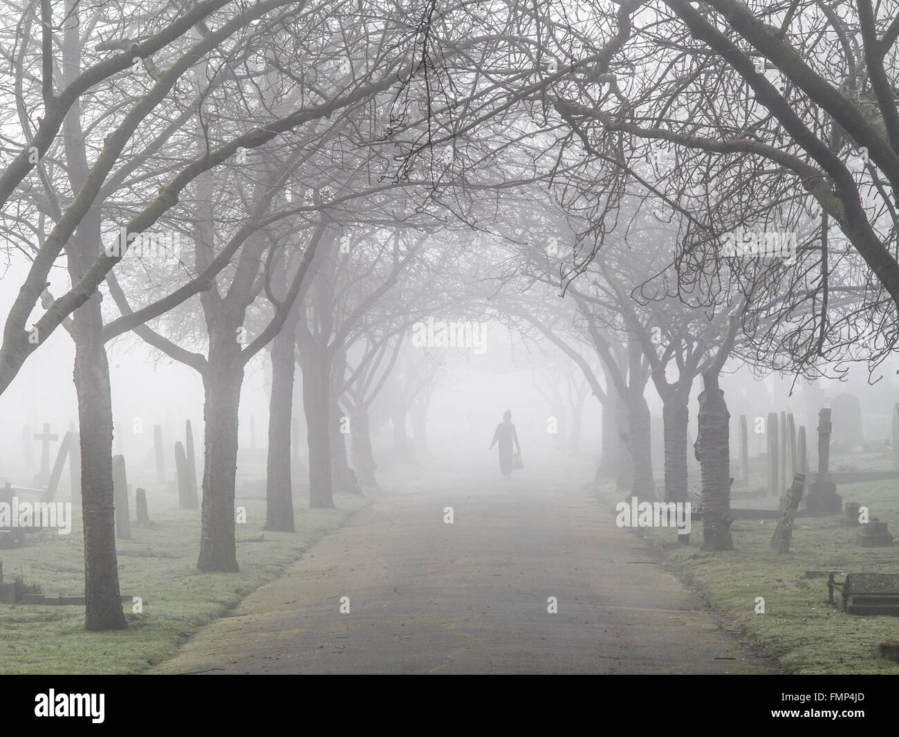 A ghostly figure walks in the fog in a graveyard Stock Photo