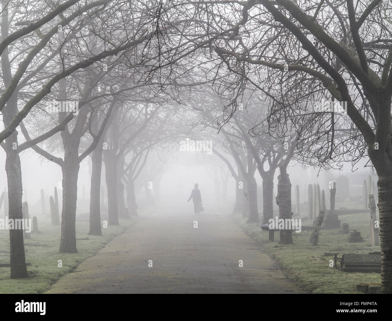 A ghostly figure walks in the fog in a graveyard Stock Photo