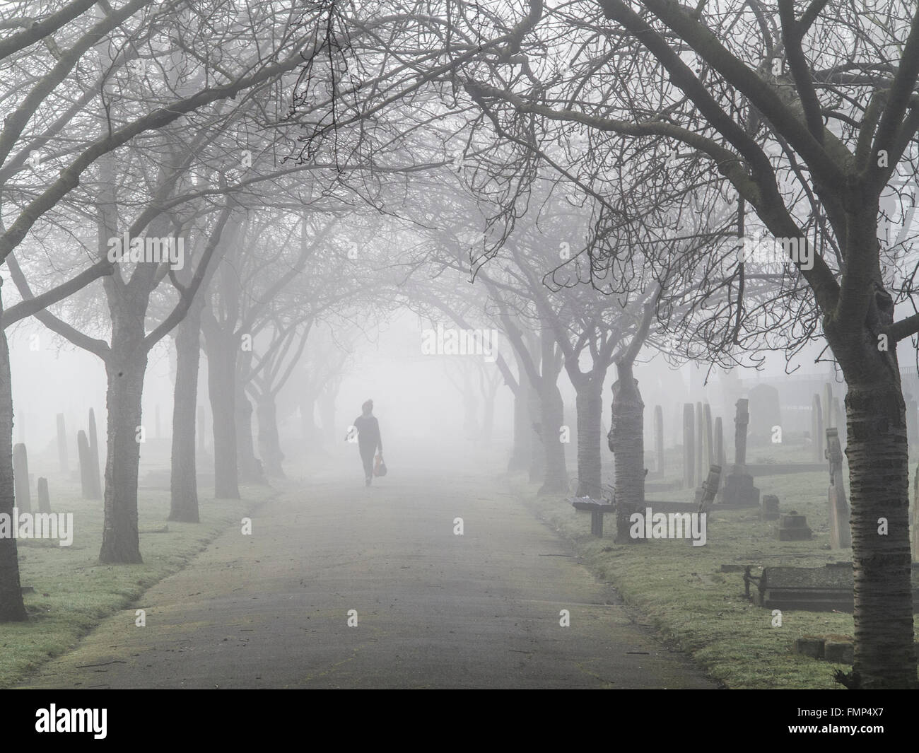 A ghostly figure walks in the fog in a graveyard Stock Photo