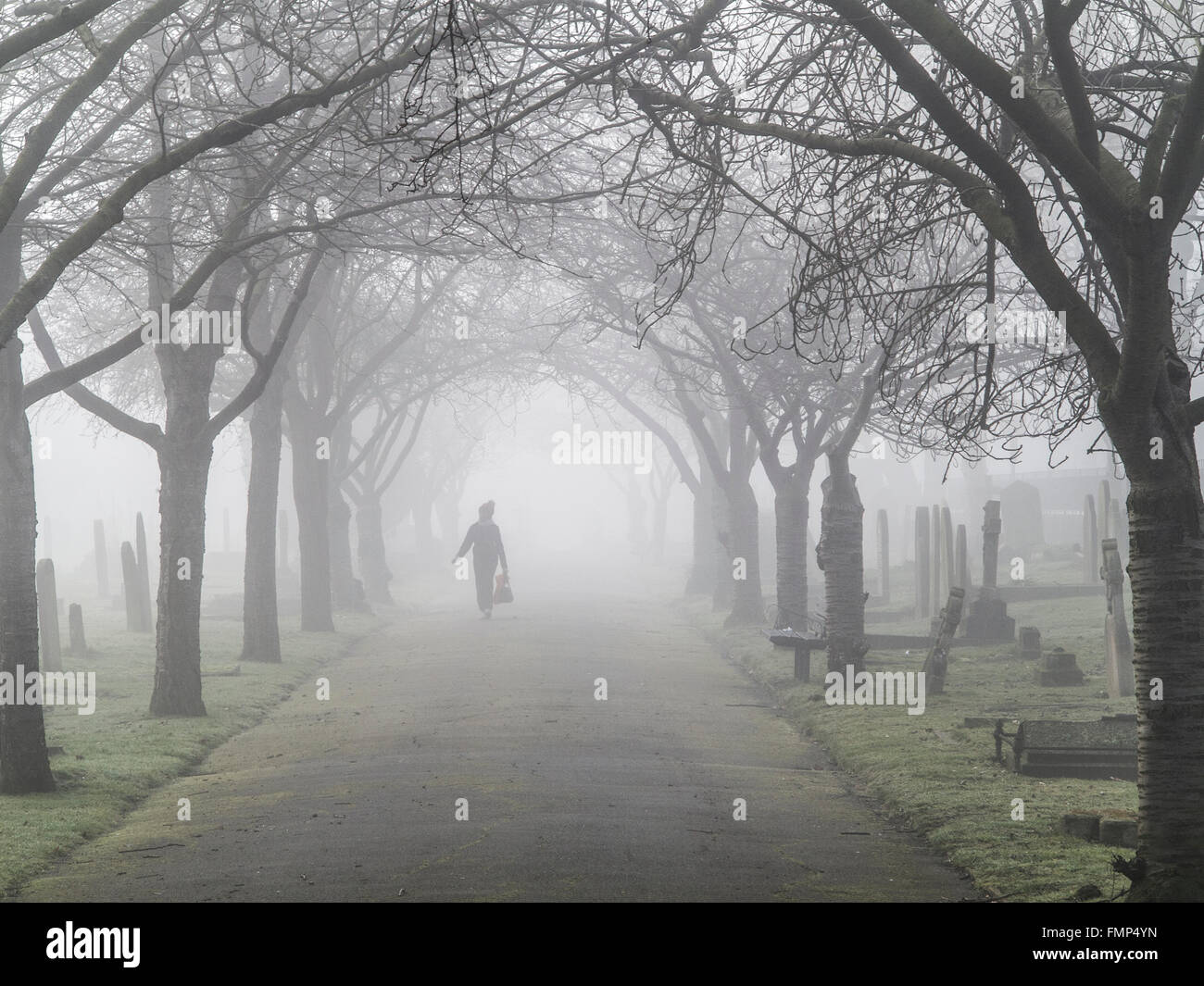 A ghostly figure walks in the fog in a graveyard Stock Photo