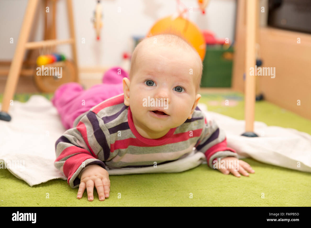 Baby, 4 months old, lying on its stomach raising its head Stock Photo