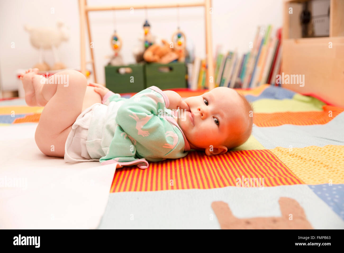 Baby, 6 months old, lying on a colourful blanket Stock Photo