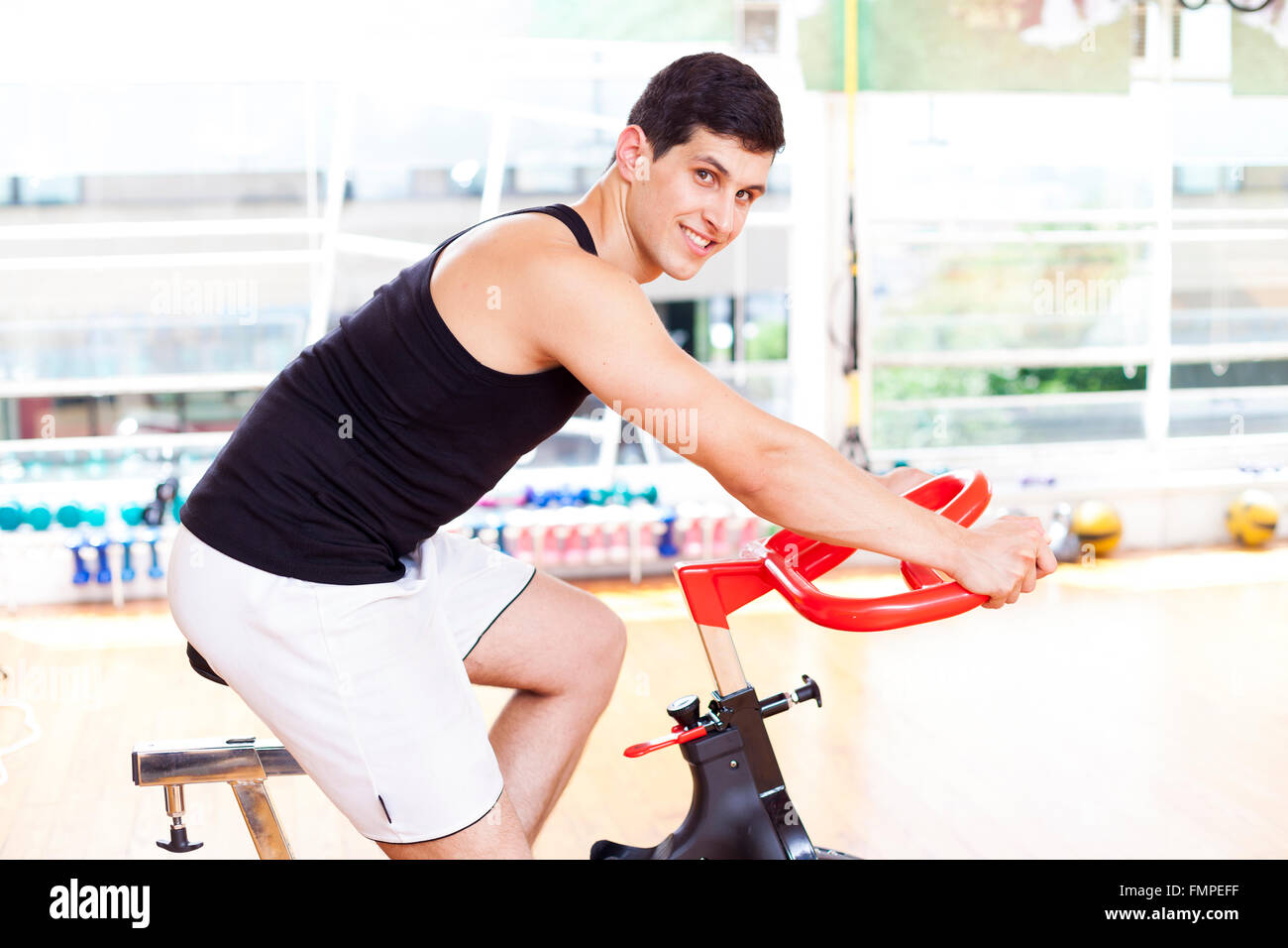 Handsome smiling man doing sport Spinning in the gym Stock Photo - Alamy