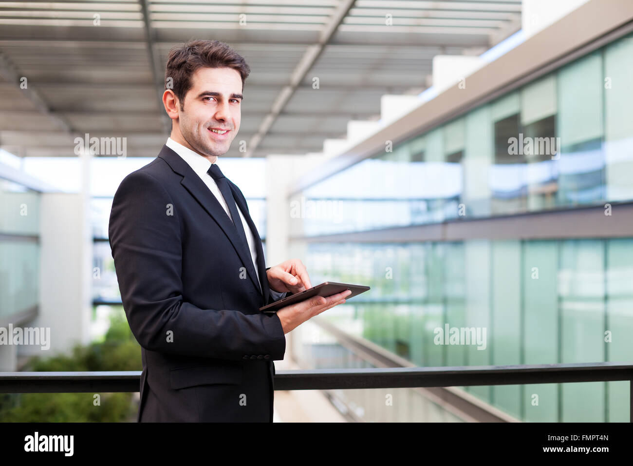 Happy smiling young businessman using his digital tablet at the office ...