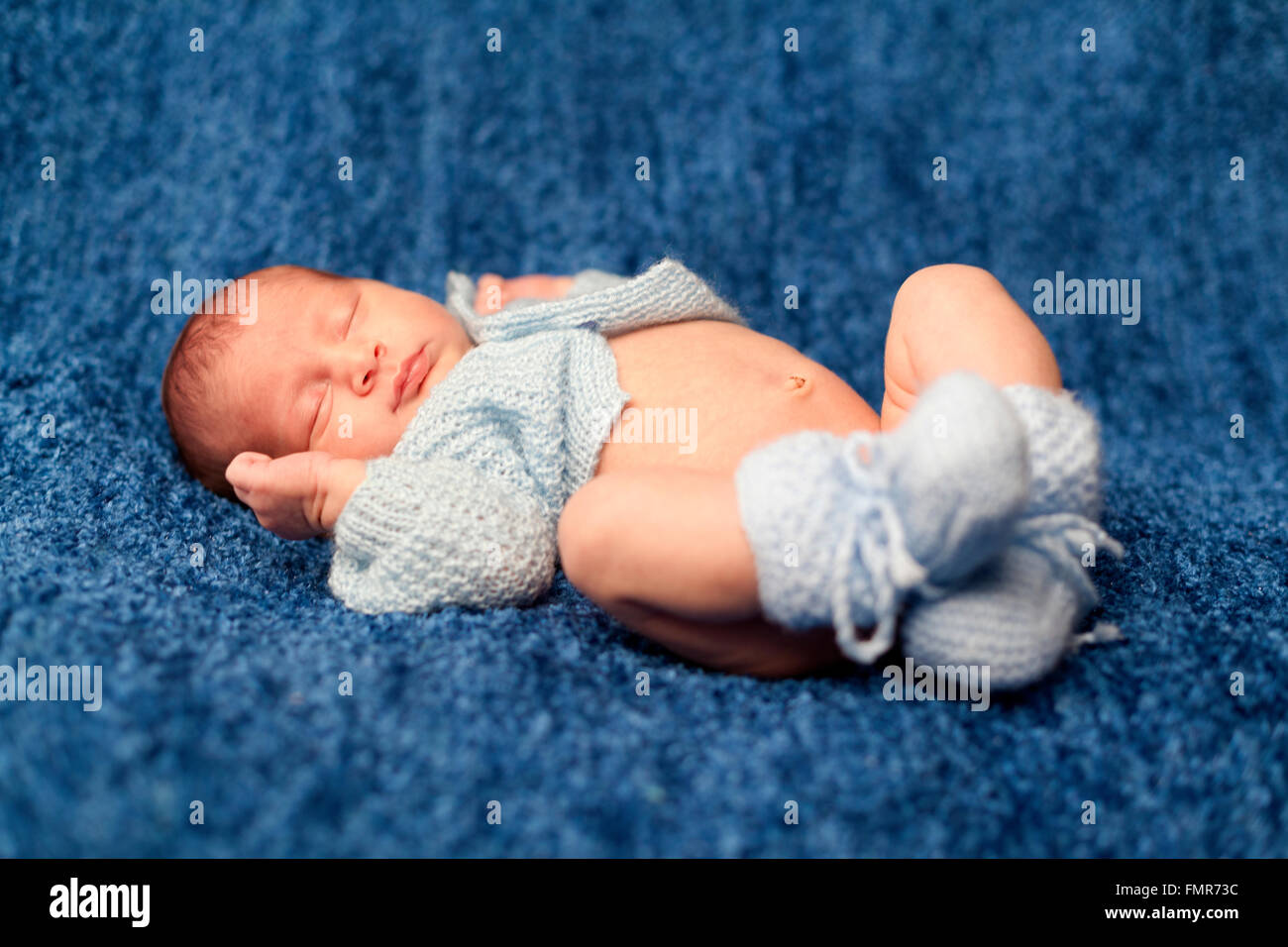 Newborn baby boy sleeping on blue blanket Stock Photo - Alamy
