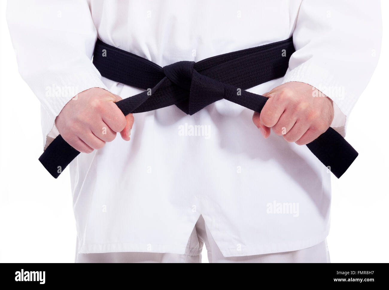 Martial arts man tying his black belt, isolated on white Stock Photo