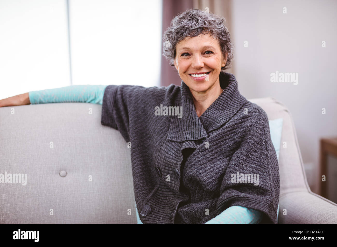 Portrait of cheerful woman sitting on sofa Stock Photo - Alamy