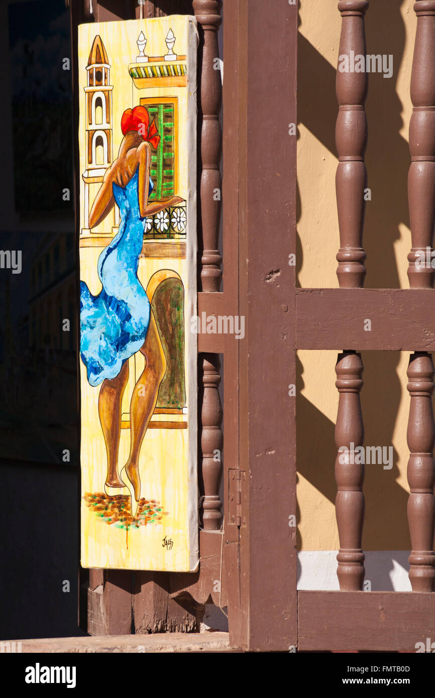Painting hanging by spindles of window shutter at Trinidad, Cuba, West