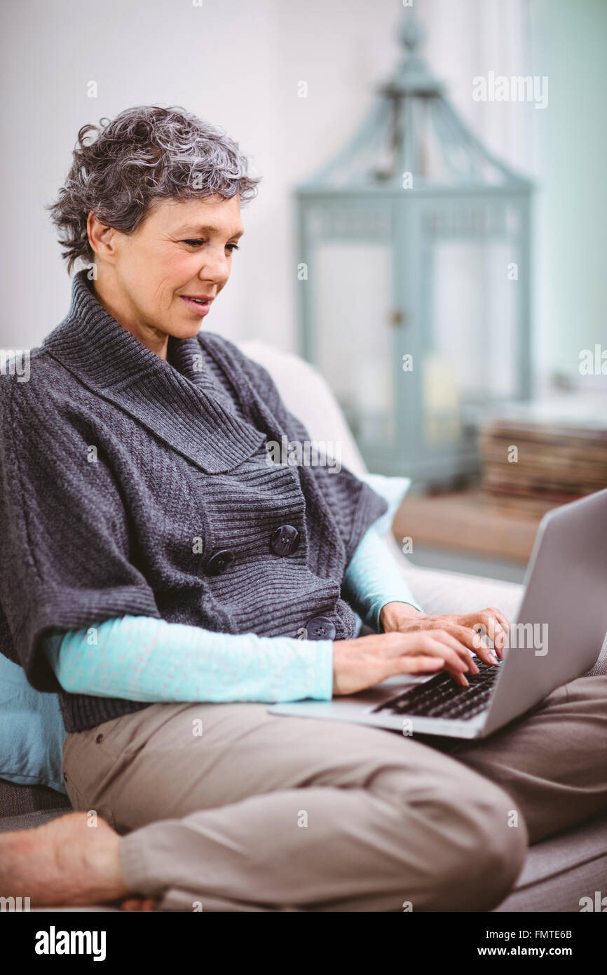 Mature woman using laptop while sitting on sofa Stock Photo - Alamy