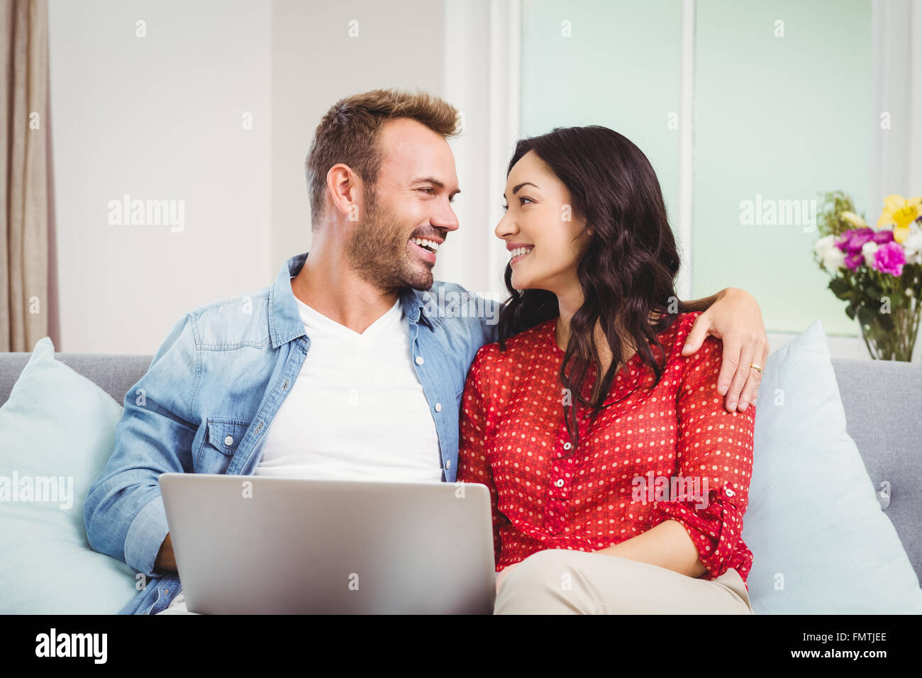 Couple with laptop siting on sofa at home Stock Photo - Alamy