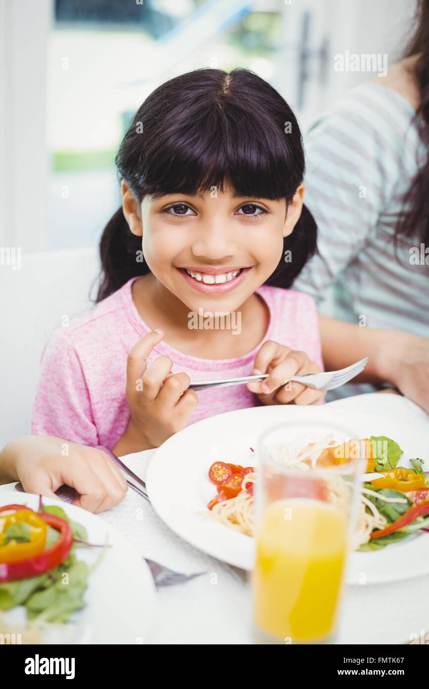 Portrait of smiling girl sitting at dining table Stock Photo - Alamy