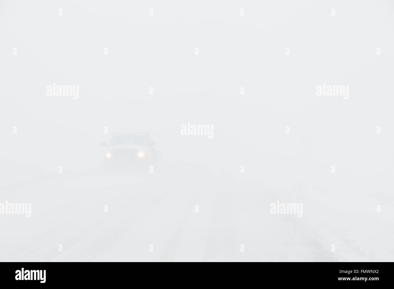 A white truck driving in zero visibility during whiteout conditions