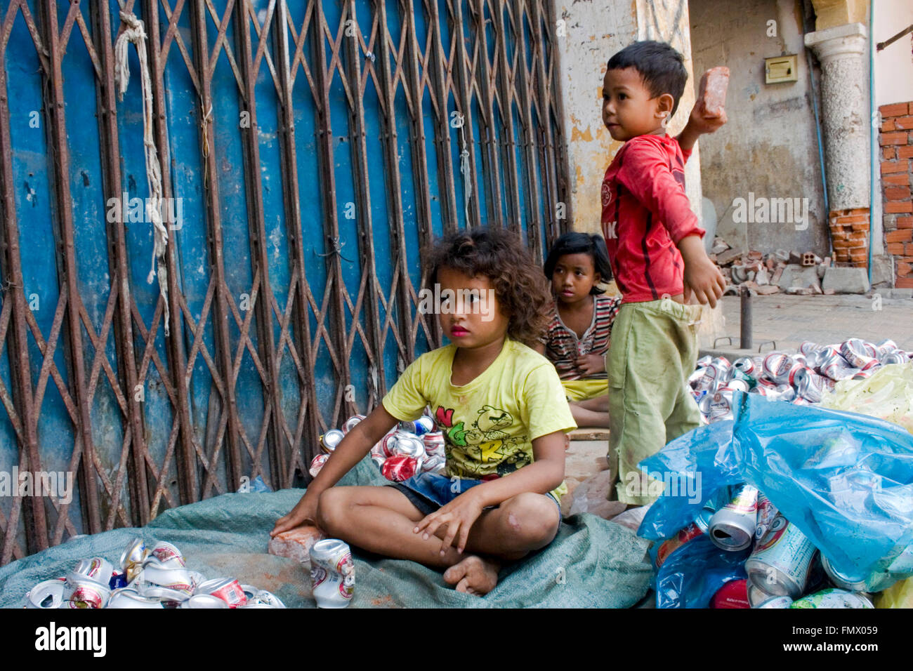 A young boy who is a scavenger prepares to throw a brick at another boy on a city street in Kampong Cham, Cambodia. Stock Photo