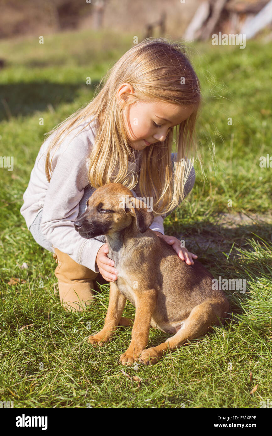 Little girl with her puppy dog , outdoor portrait, early springtime. Stock Photo