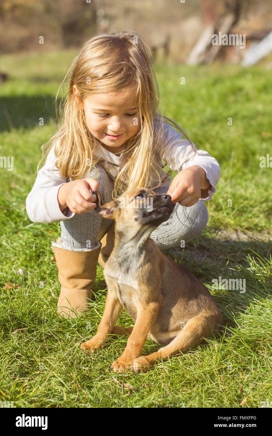 Little girl with her puppy dog , outdoor portrait, early springtime. Stock Photo