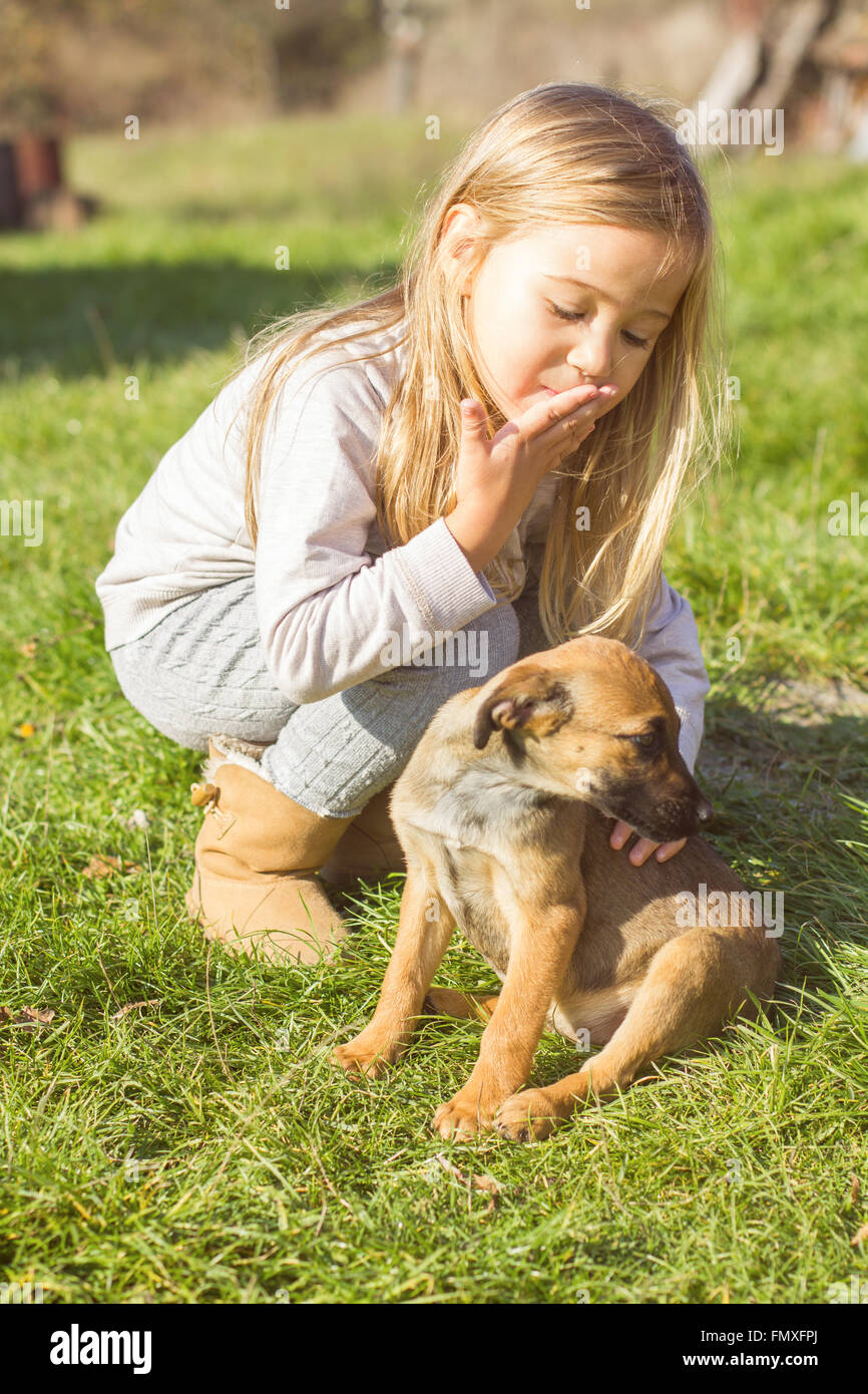 Little girl with her puppy dog , outdoor portrait, early springtime. Stock Photo