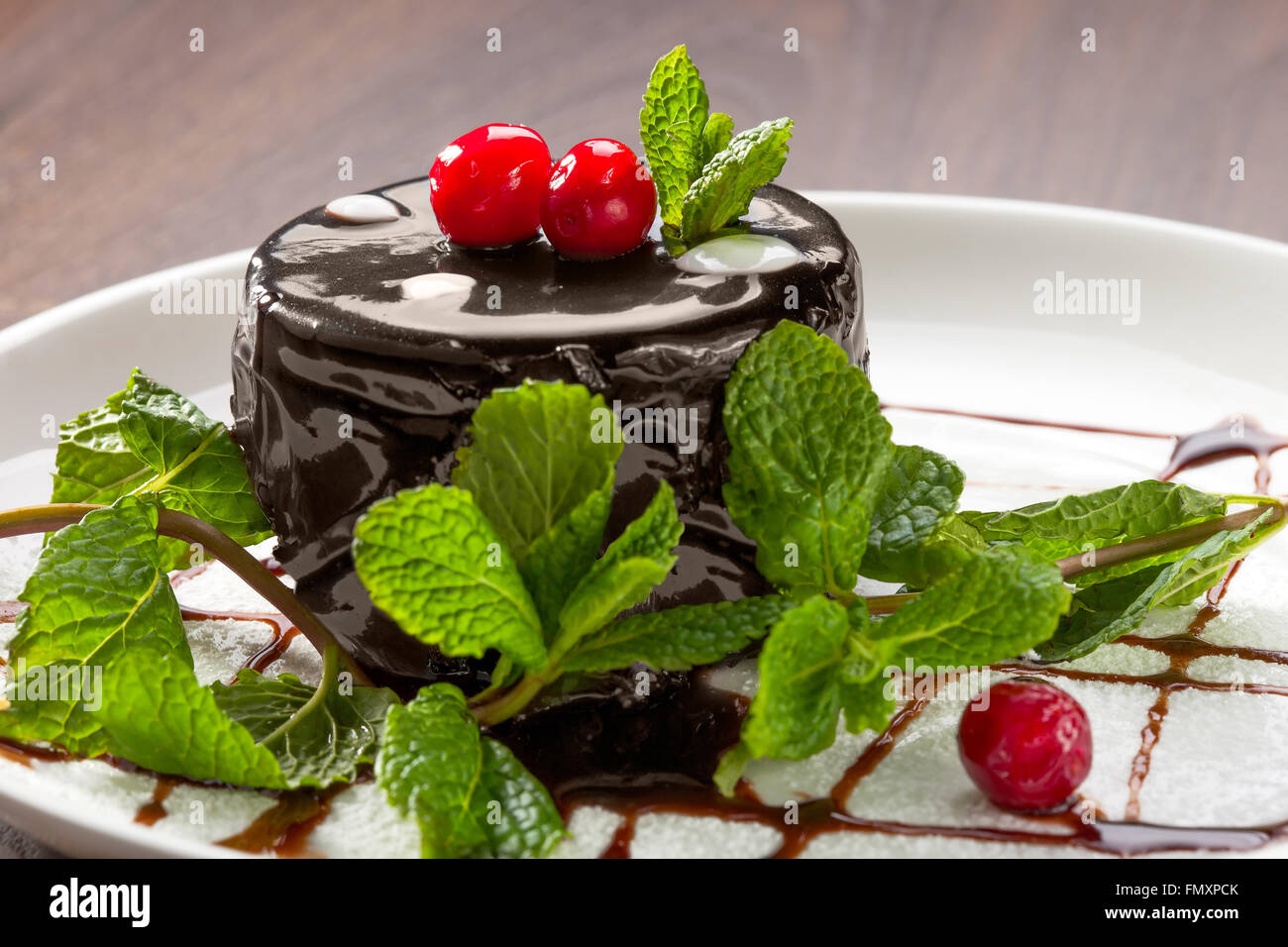 Chocolate cake, decorated with cherries and mint on a plate with ...