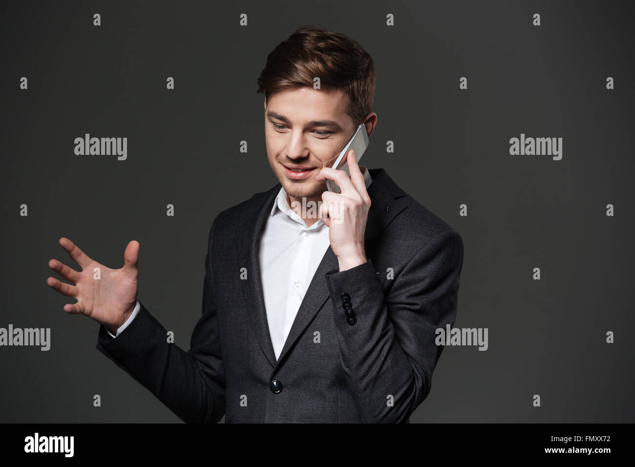 Smiling handsome young businessman in black suit gesturing and talking ...