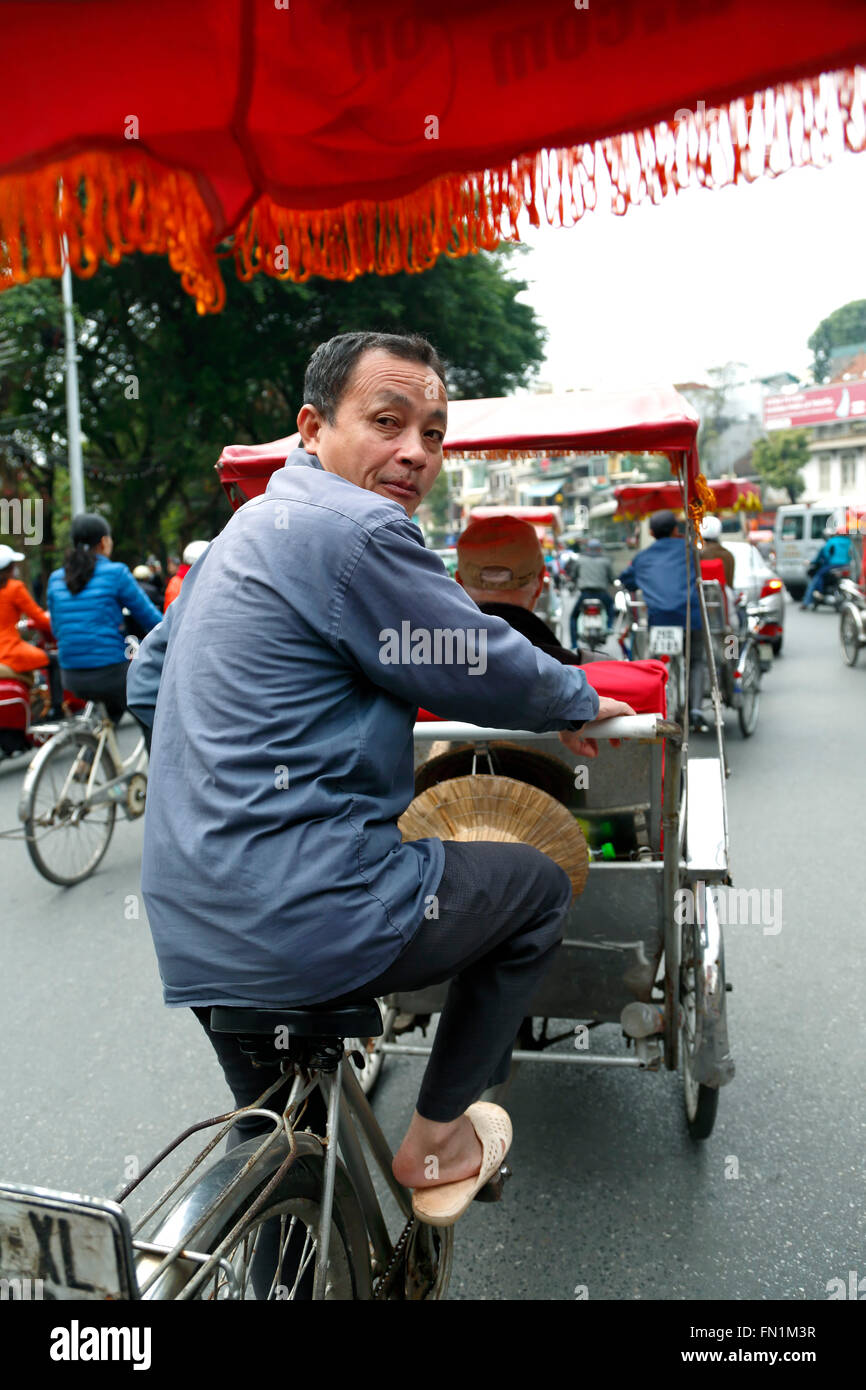 Cyclo (three-wheel bicycle taxi) driver in traffic, Old Quarter, aka The 36 Streets, Hanoi, Vietnam Stock Photo