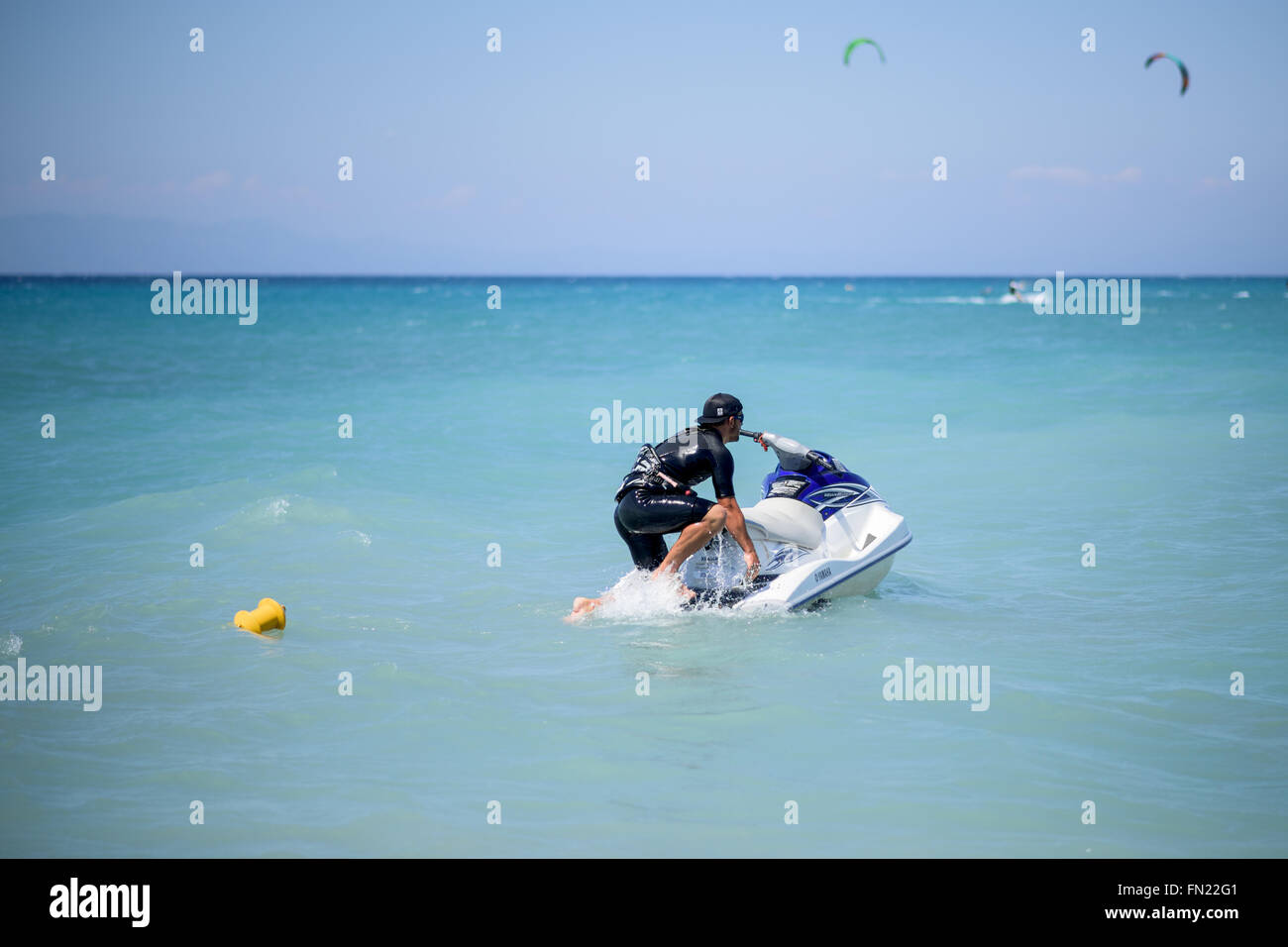 A guy getting on a water scooter in the sea Stock Photo
