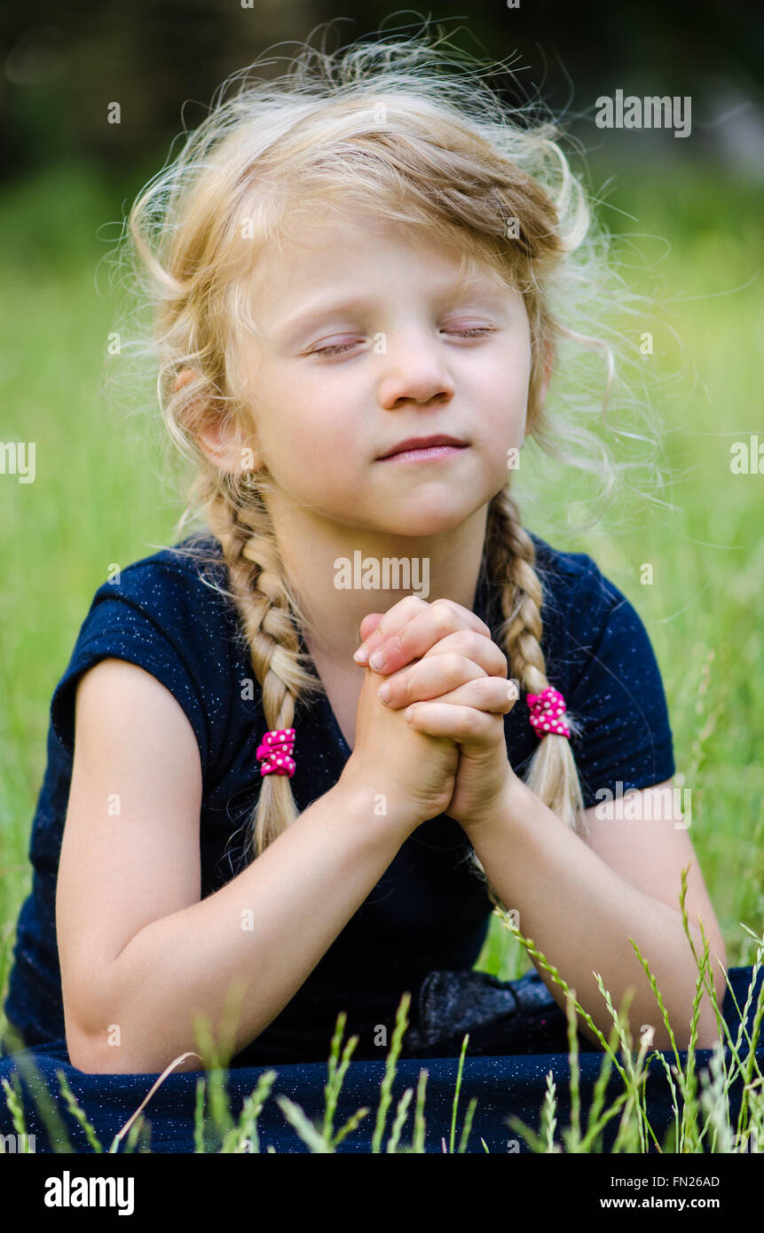portrait of blond girl with braided hair praying Stock Photo