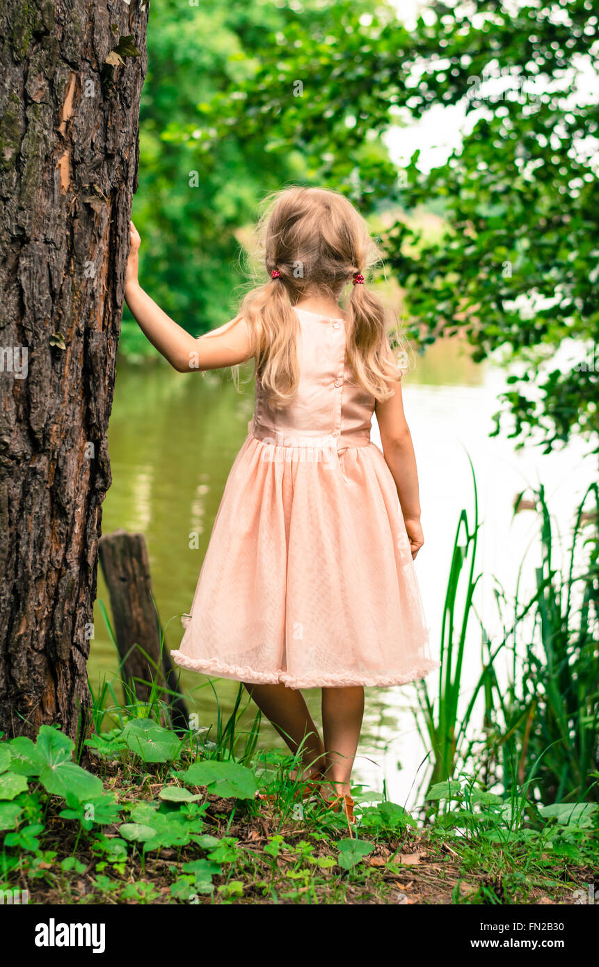 little blond girl with long hair looking to the pond Stock Photo