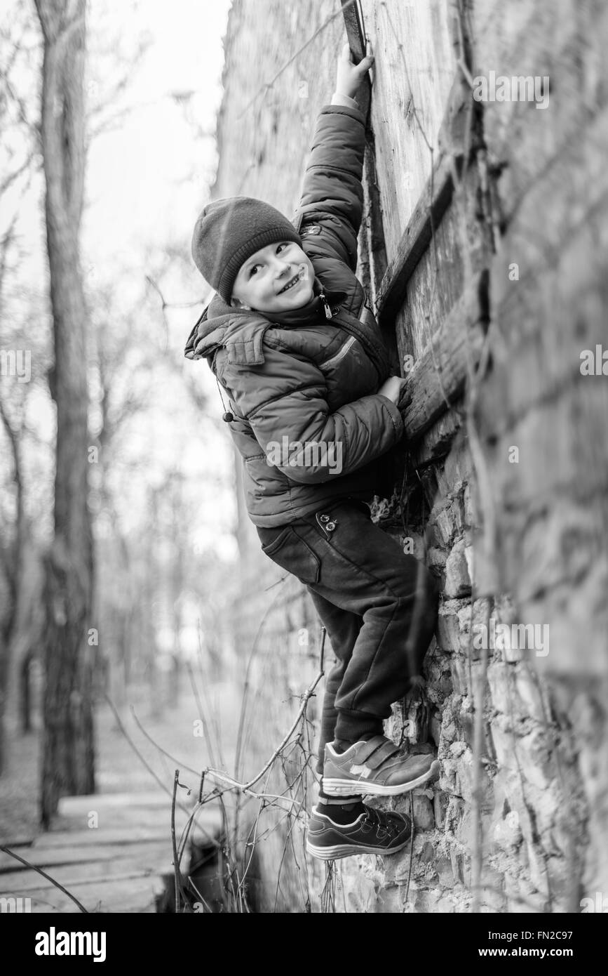 little boy climbs up the textured wall Stock Photo