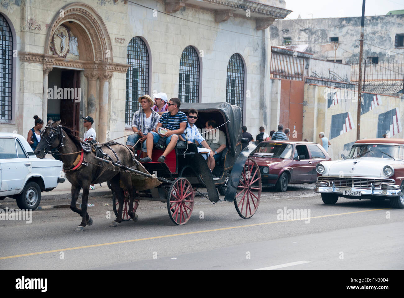 A horse drawn carriage followed by a vintage Ford Fairlane escort tourists on the famous Malecon in Havana Cuba. Stock Photo