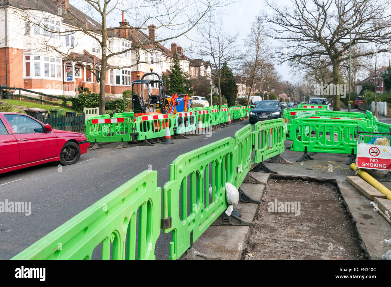 Traffic passing though roadworks on a suburban residential street. Caused by replacement of gas mains. Stock Photo