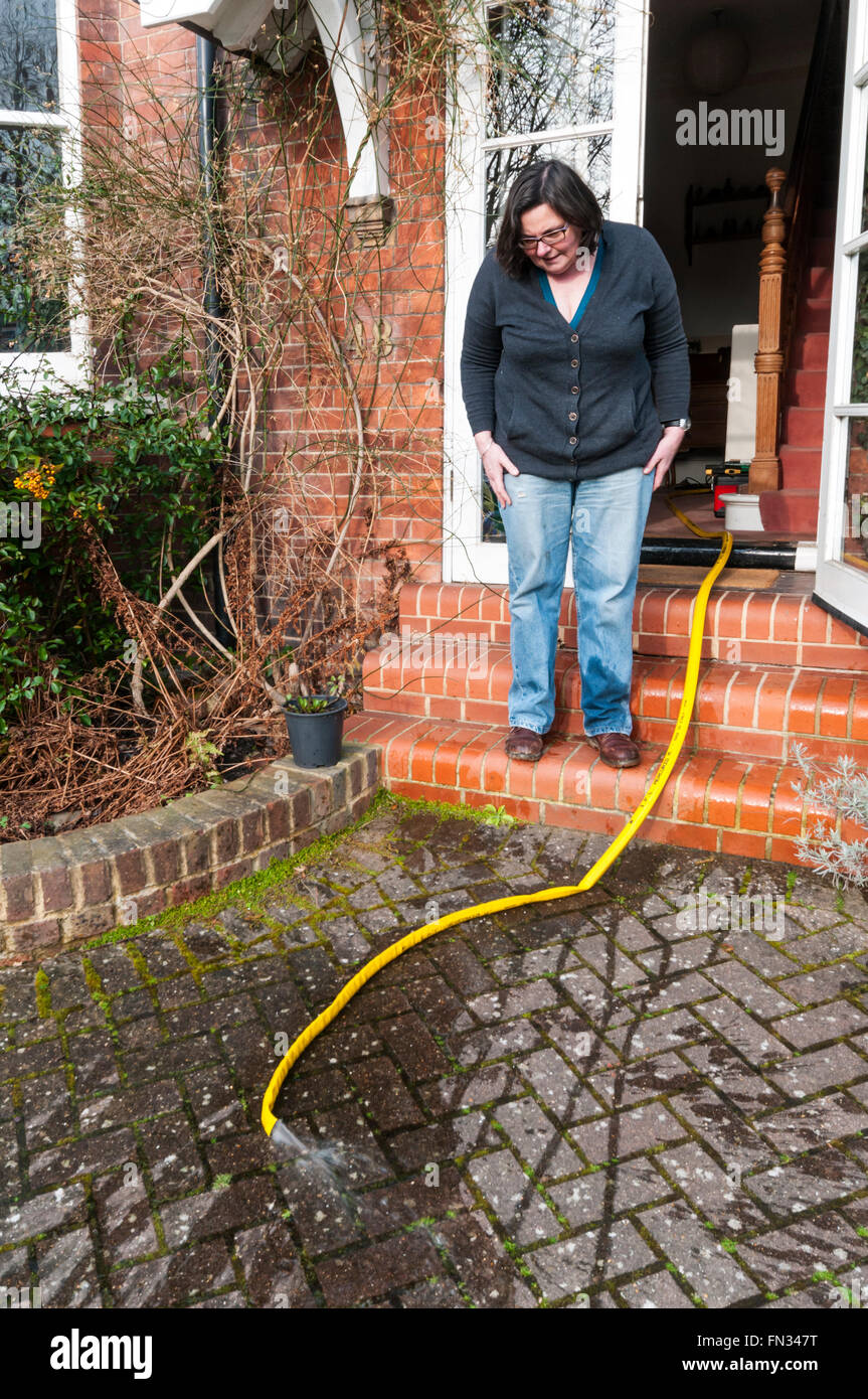 Woman pumping out her flooded cellar after rain. Stock Photo