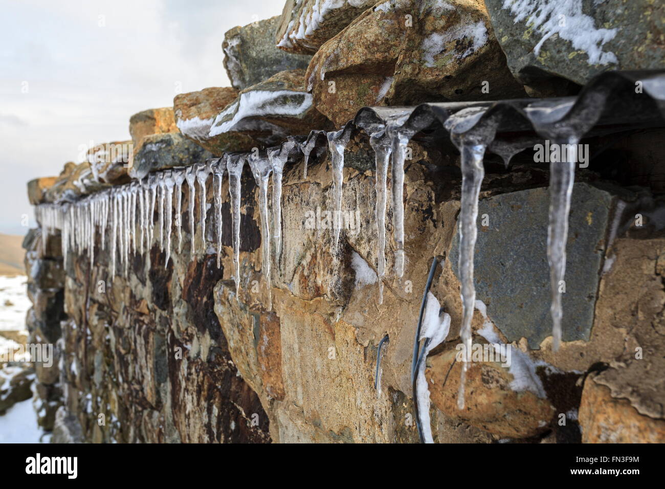 Icicles hang from the hikers shelter on top of Cadair Idris Stock Photo