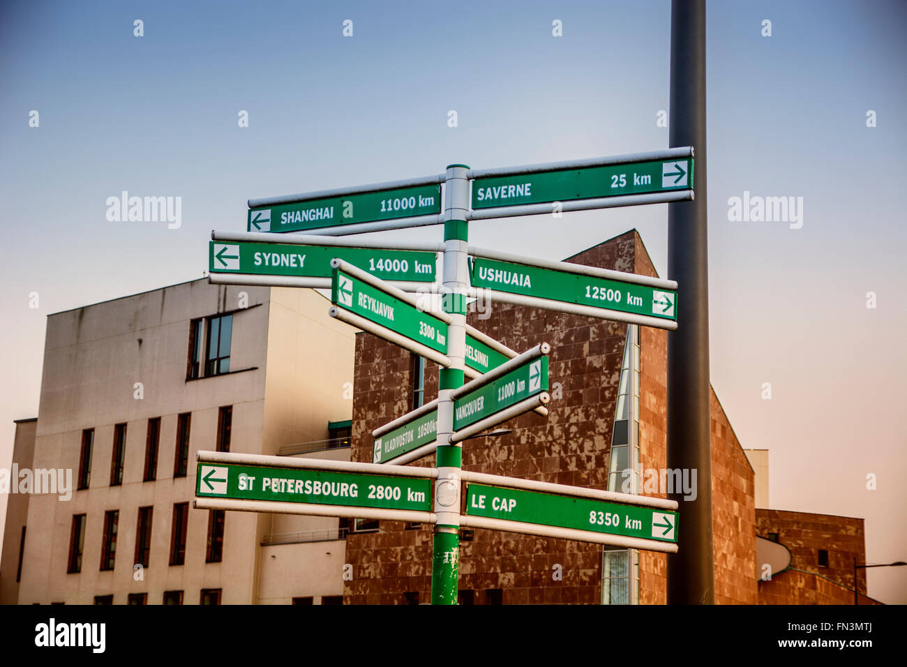 Different geographical locations on crossroad signs against of buildings Stock Photo
