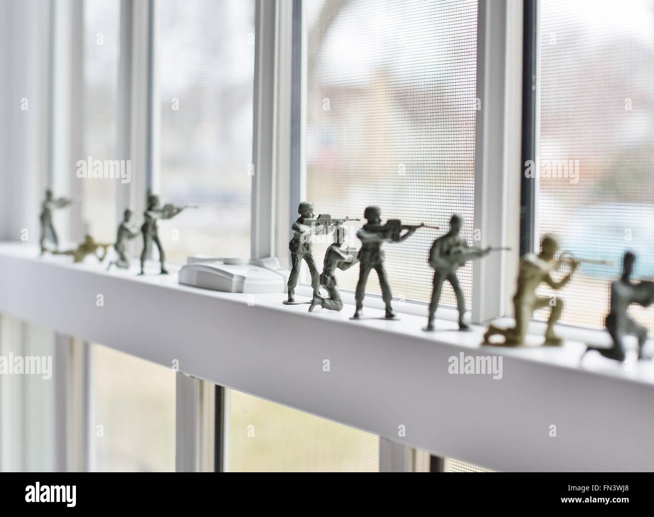 Plastic toy soldiers lined up on a windowsill. Stock Photo