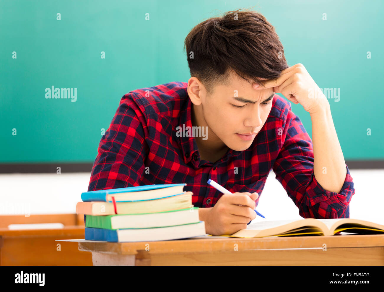 Stressed student  studying for exam in classroom Stock Photo