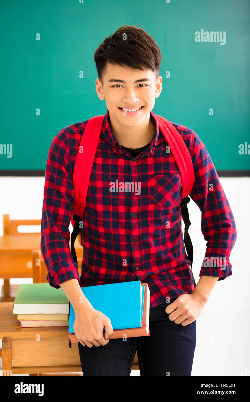 Smiling male student standing in  classroom Stock Photo