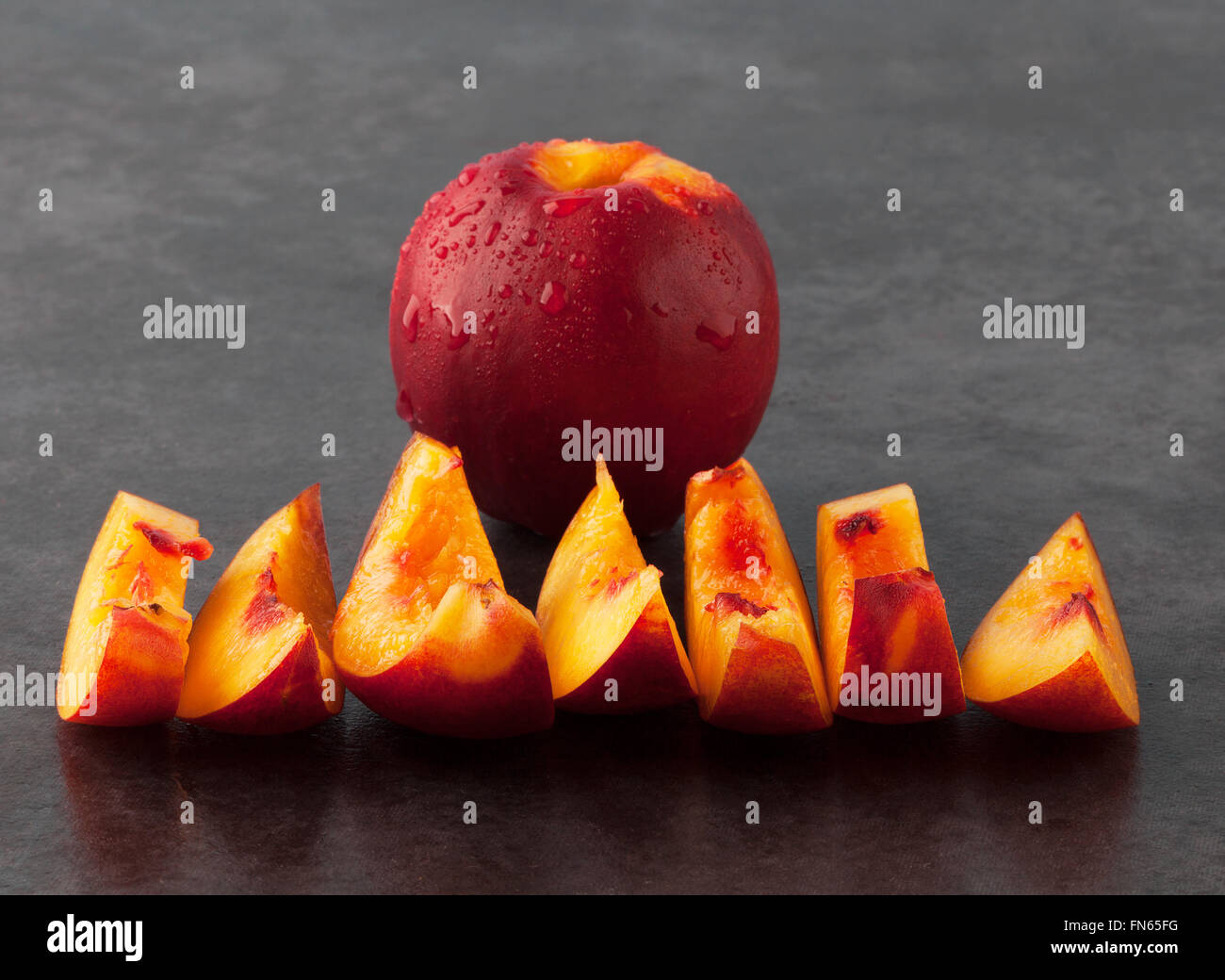 Yellow nectarine peach whole fruit and slices on dark grungy background. Shallow depth of