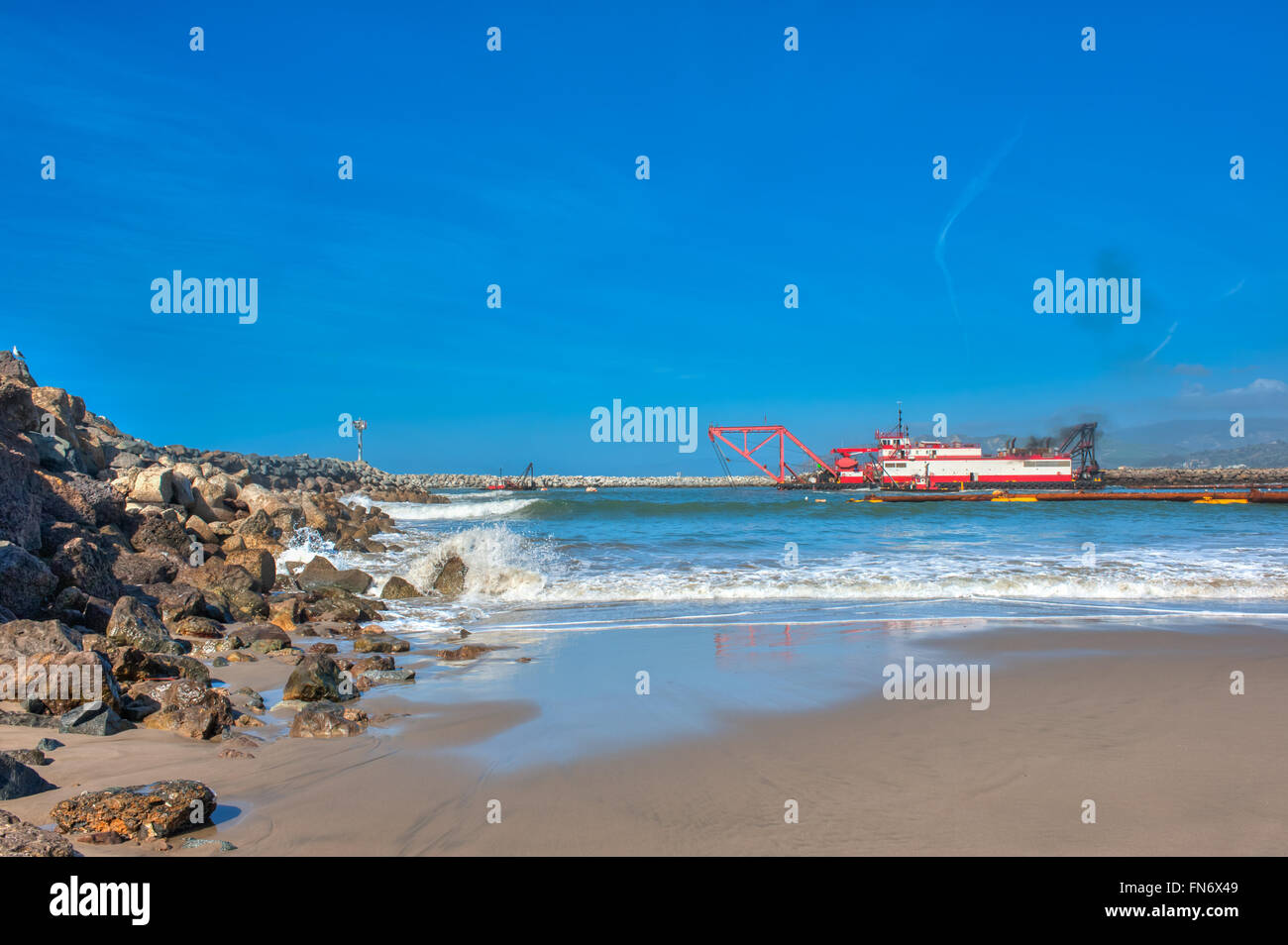 Dredge barge along the rock jetty Stock Photo