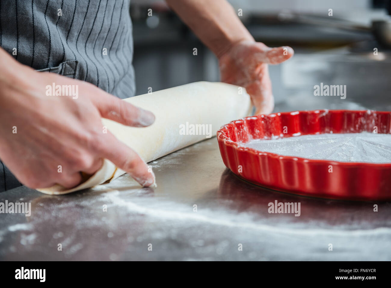 Hands of professional male chief cook making pie in baking pan on the kitchen Stock Photo