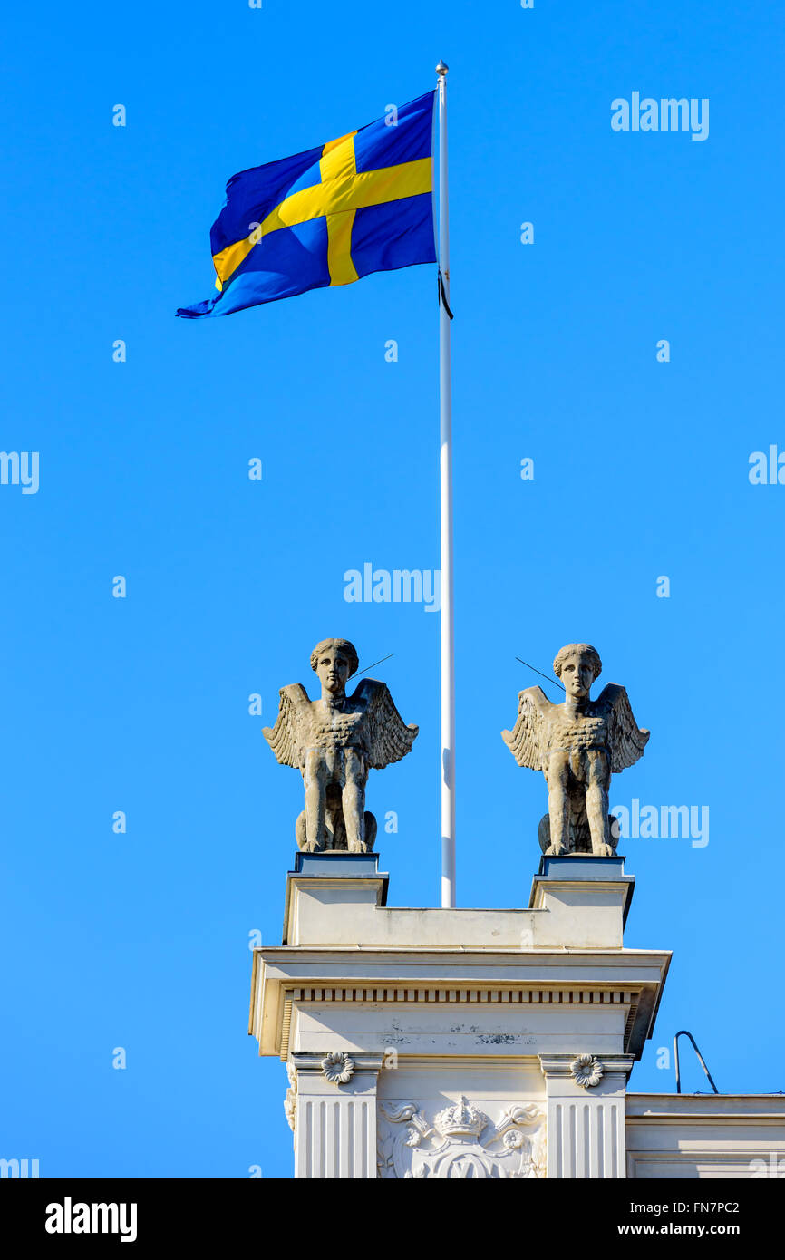 Lund, Sweden - March 12, 2016: The Swedish colors fly in the wind on top of the main building of Lund university. Four sphinxes Stock Photo
