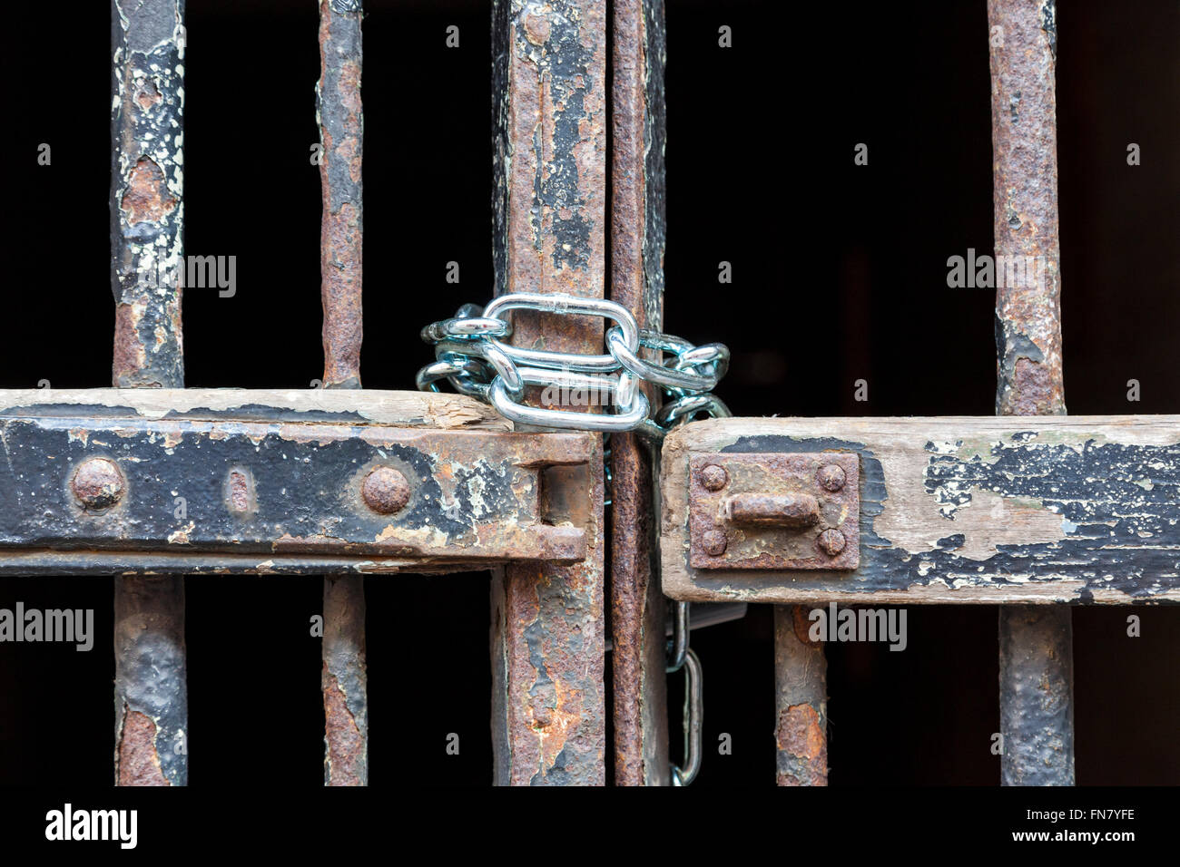 Old wooden and rusty metal gate with peeling paint chained up with a new chain, England, UK Stock Photo