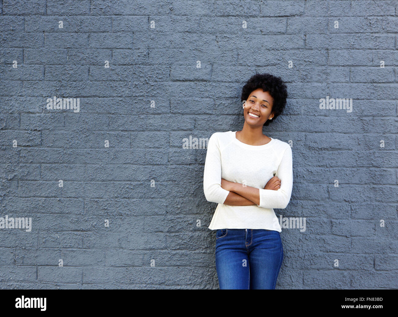 Portrait of confident young african woman standing against a gray wall Stock Photo