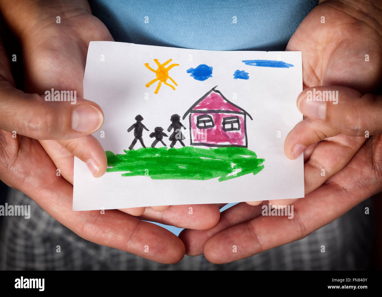 Child and his mom holding a drawn house with family. Close up.