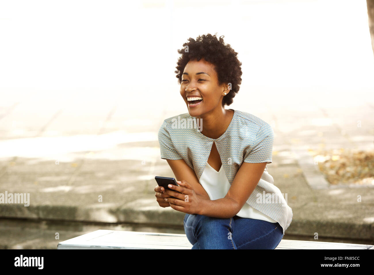 Portrait of beautiful young african woman smiling while sitting outside ...