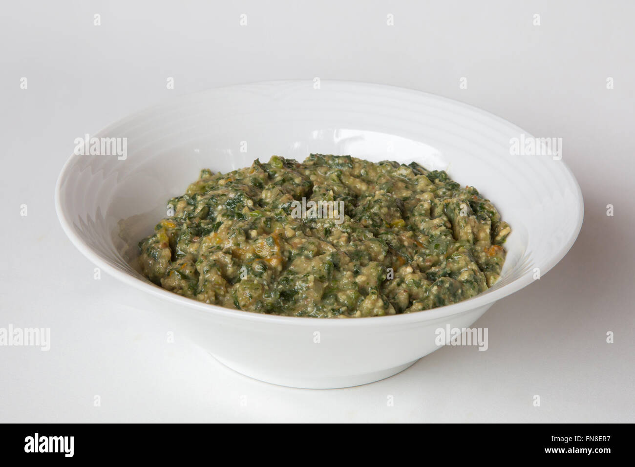 A bowl umbhidvo wetintsanga consisting of cooked  pumpkin leaves, shoots and ground nuts - a traditional Swazi dish Stock Photo