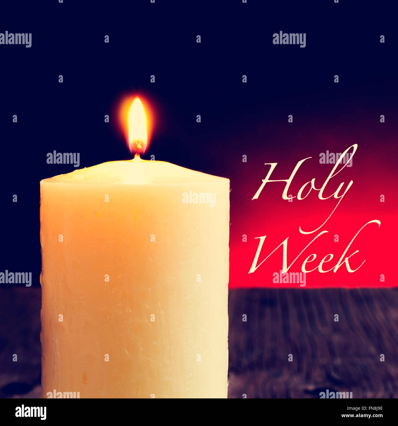 closeup of a lit candle on a rustic wooden surface and the text holy week Stock Photo