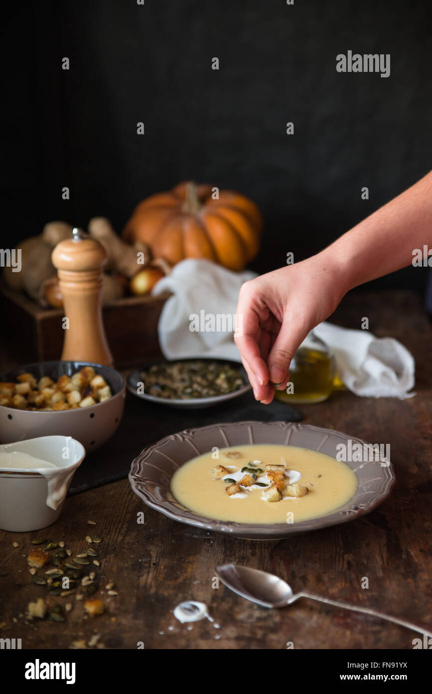 Boy seasoning bowl of potato soup Stock Photo