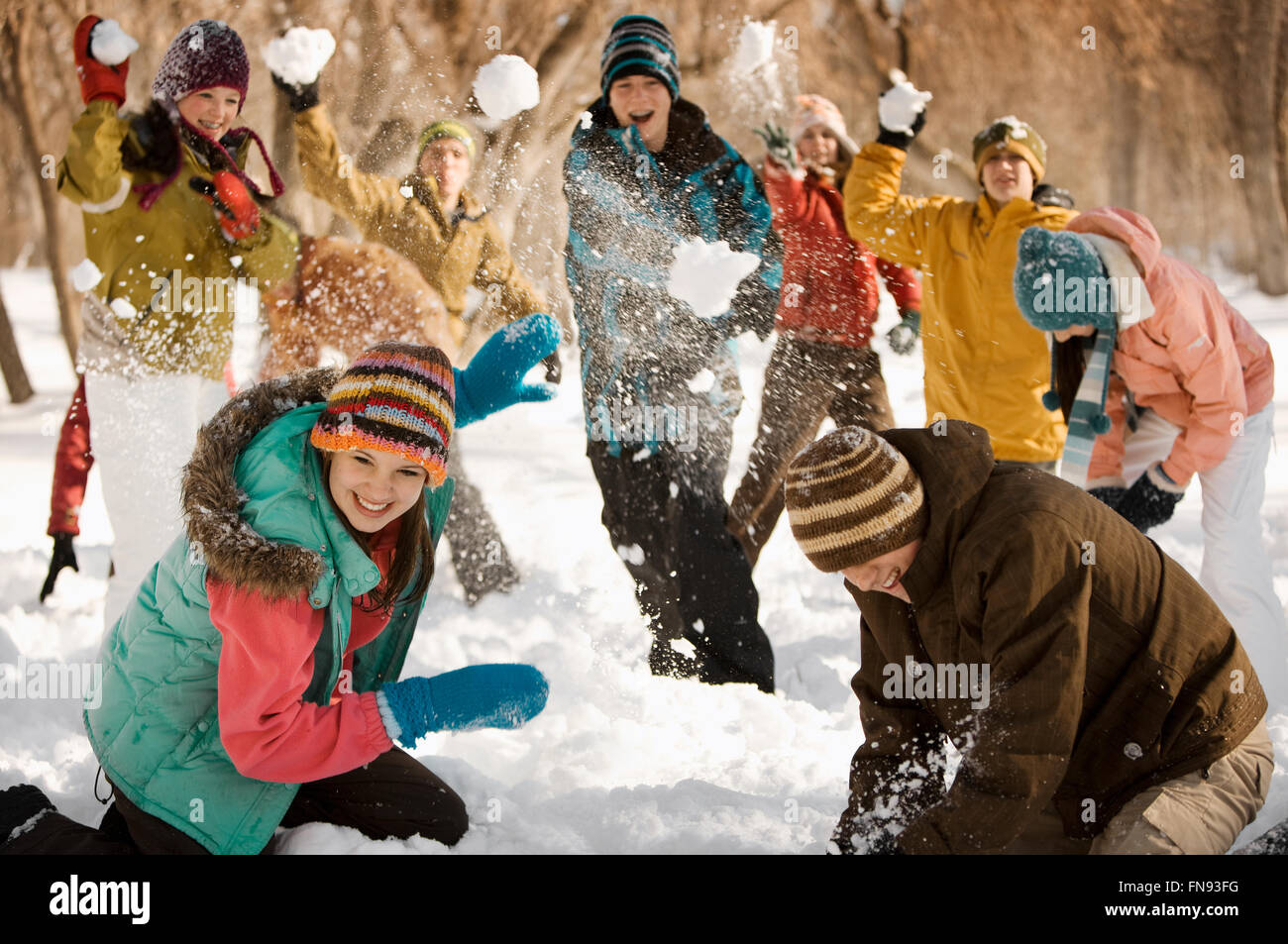 A group of young people, boys and girls having a snowball fight. Stock Photo