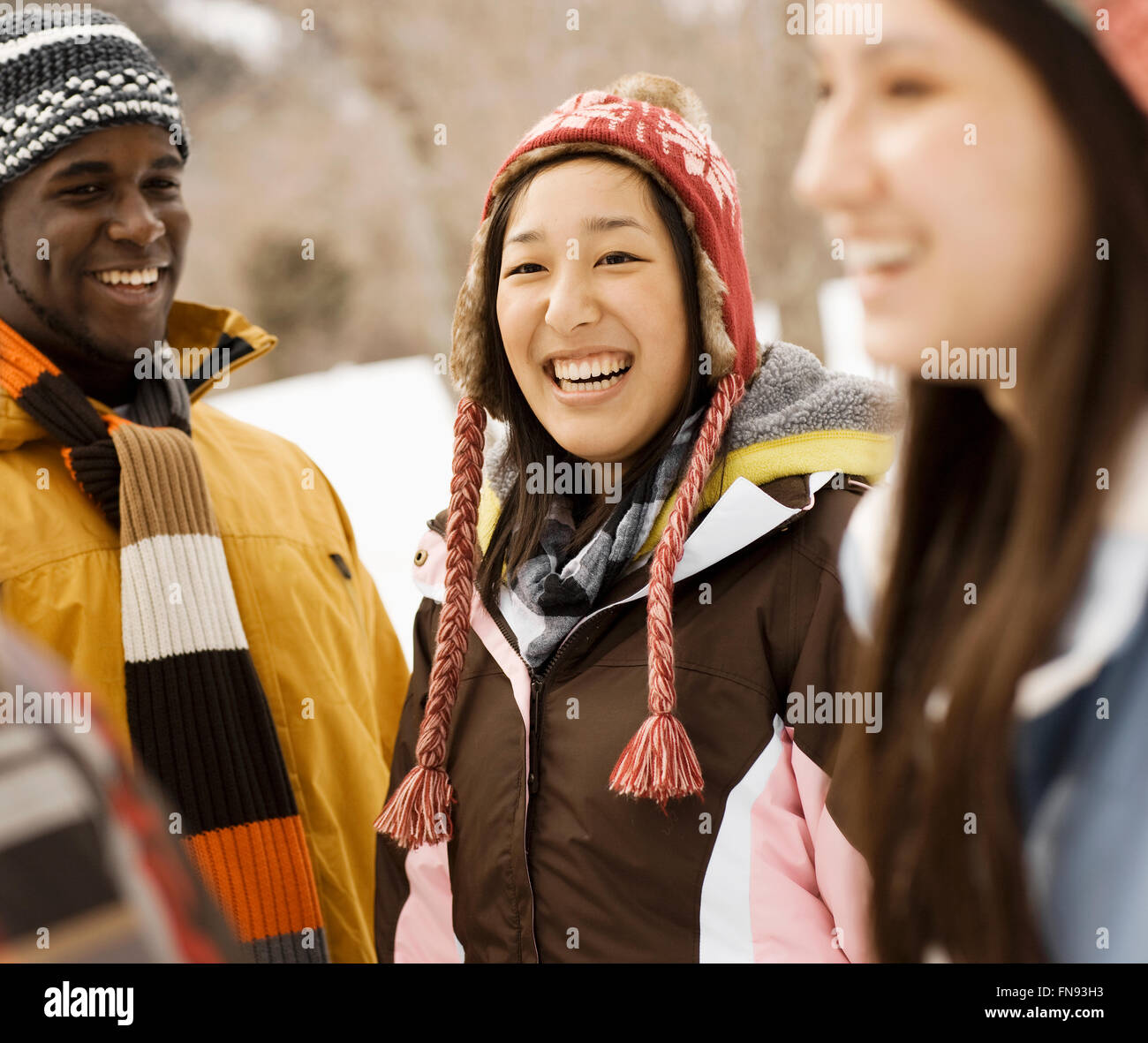 Three young people, two women and a man in hats and scarves. Stock Photo