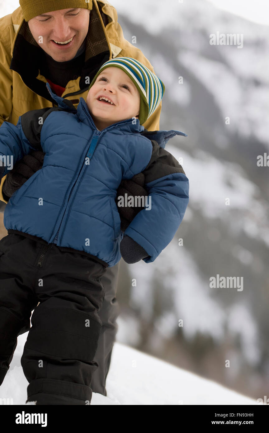 A man with a young child wrapped up against the cold, in the mountains ...