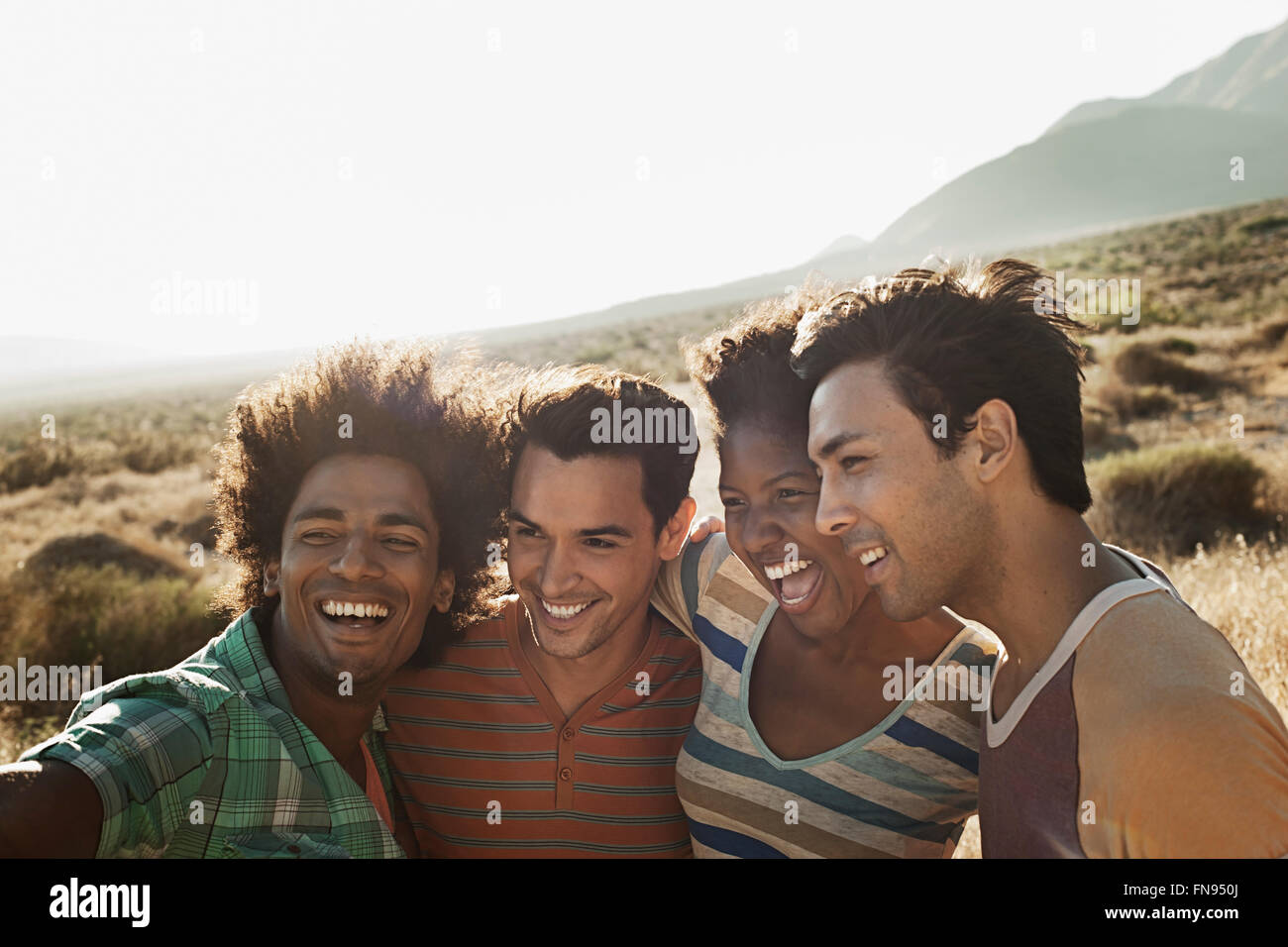 A group of friends, men and women, heads together posing for a selfy in the heat of the day. Stock Photo